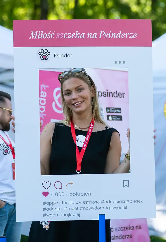 Osoba na evencie Psindera trzymająca ramkę z hasłem „Miłość szczeka na Psinderze”